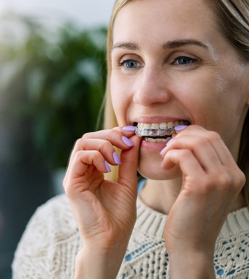 a woman putting clear aligners in her mouth