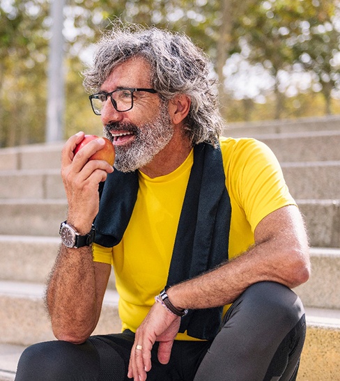 a man with glasses eating an apple