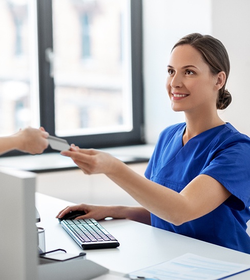 a woman in scrubs accepting a payment from a patient