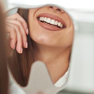 Woman’s perfect teeth reflected in tooth-shaped mirror