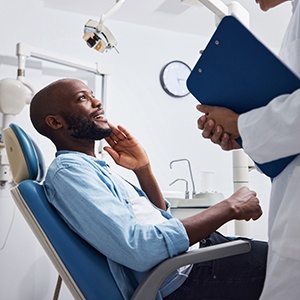 Smiling patient talking to dentist with clipboard